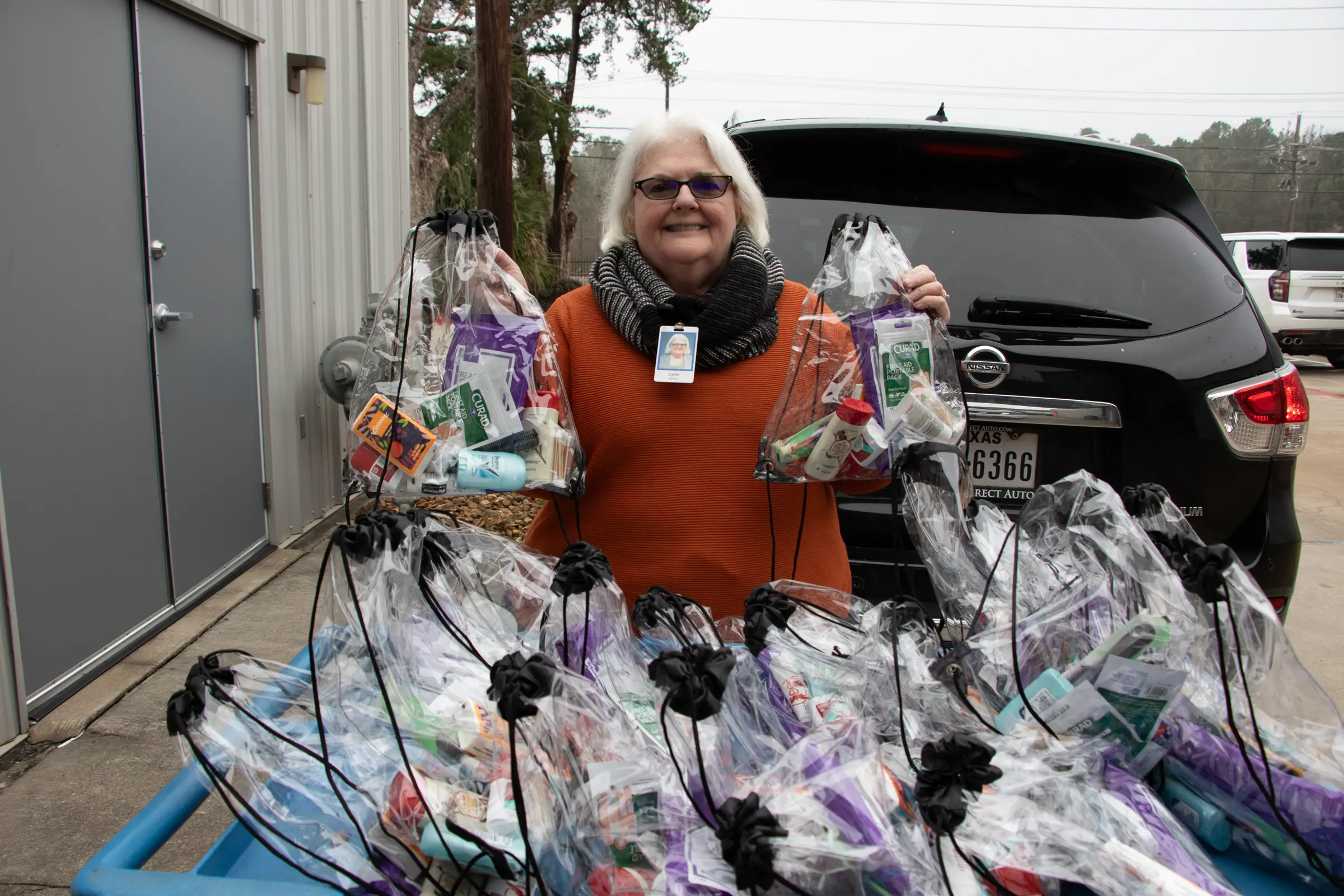 A volunteer holds clear bags packed with hygiene items.
