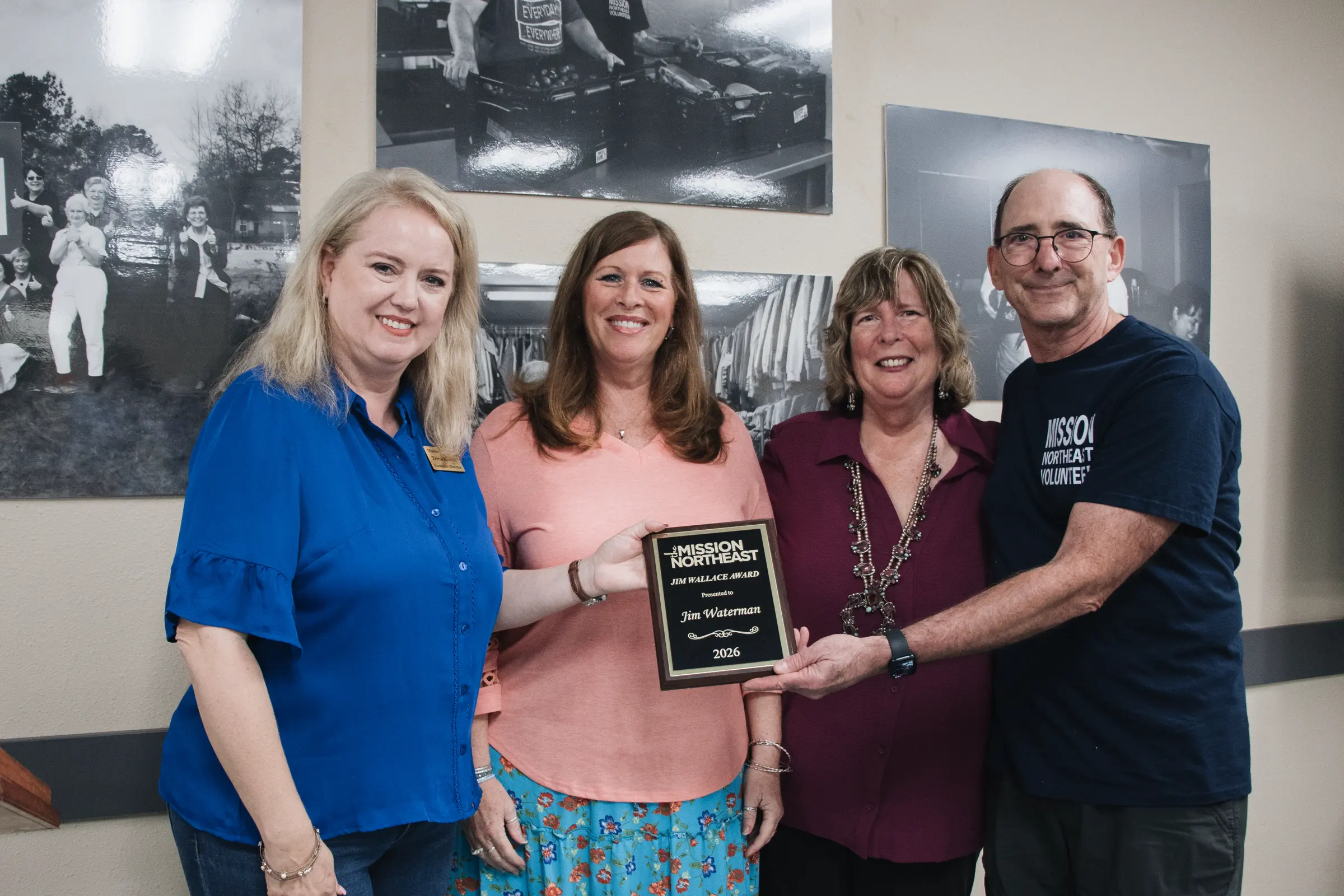 Four people hold the Jim Wallace Award plaque.